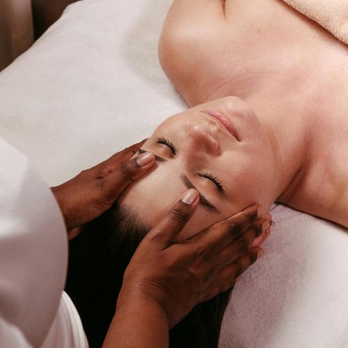 Person lying down, eyes closed, receiving Access Bars